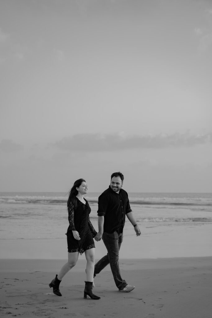 Romantic pre-wedding couple walking along the peaceful shoreline of Diu during an evening beach photoshoot.