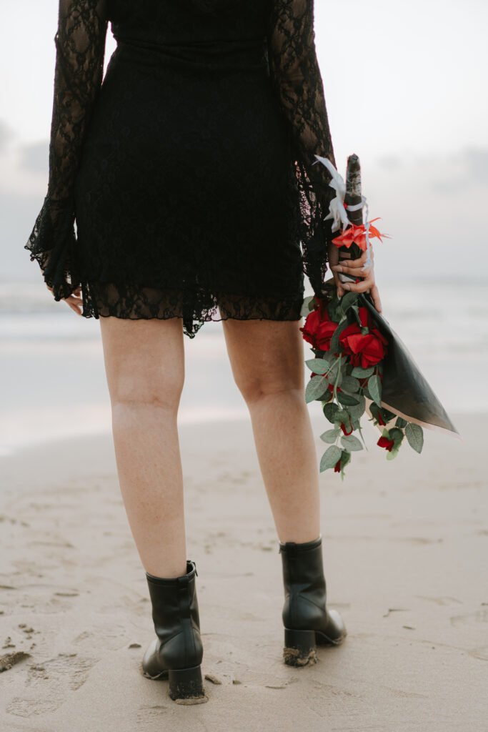 Romantic beach portrait with red roses captured during a couple pre-wedding photoshoot in Diu.